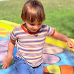 child playing in colorful playground wearing 80s style striped ringer tee