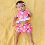 Cute stylish baby wearing adorable pink flower power outfit set on yellow background 