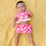 Cute stylish baby wearing adorable pink flower power outfit set on yellow background 