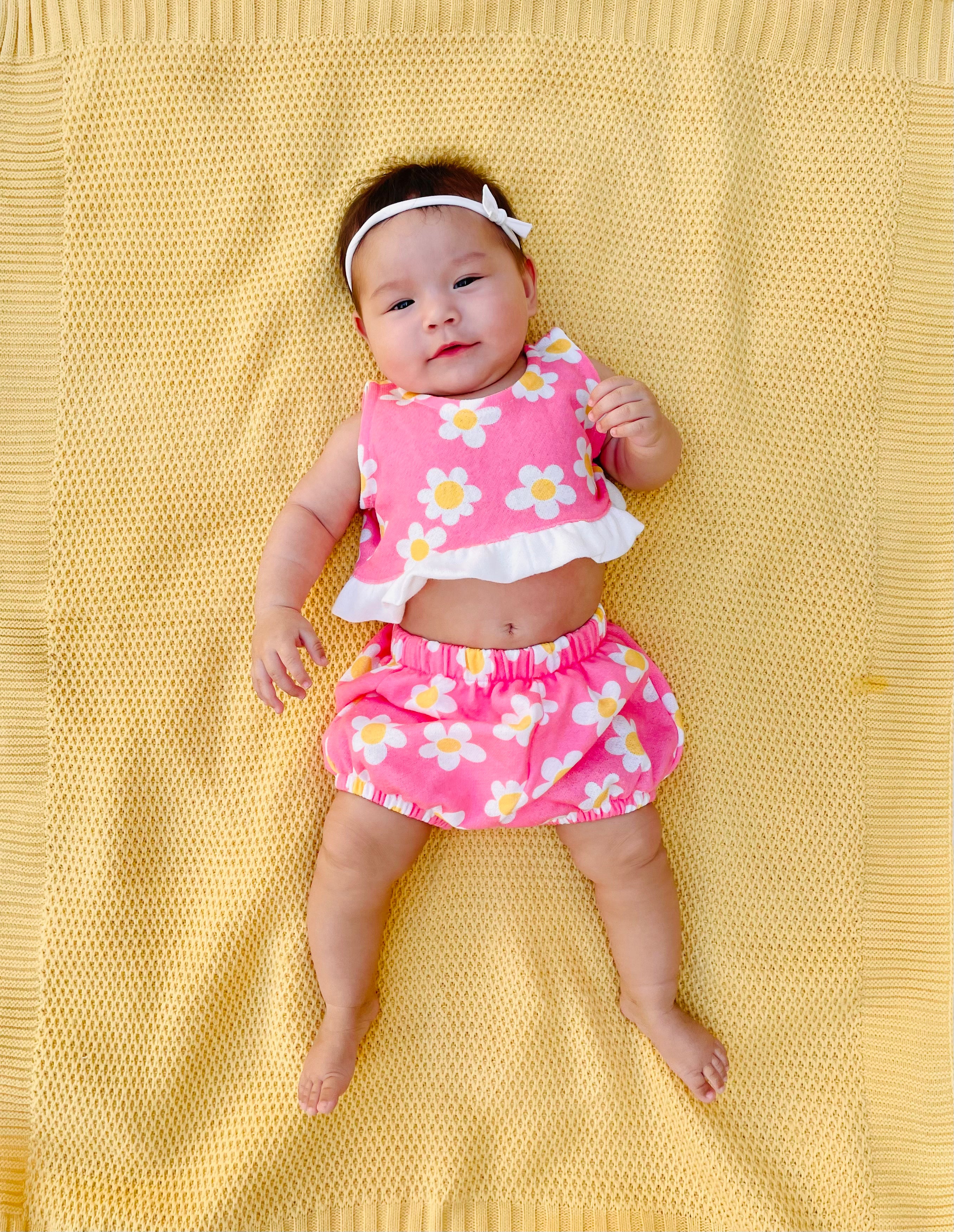 Cute stylish baby wearing adorable pink flower power outfit set on yellow background 