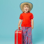 child wearing cool outfit with red shirt, vintage style wide leg striped pants, holding a red suitcase and a blue background