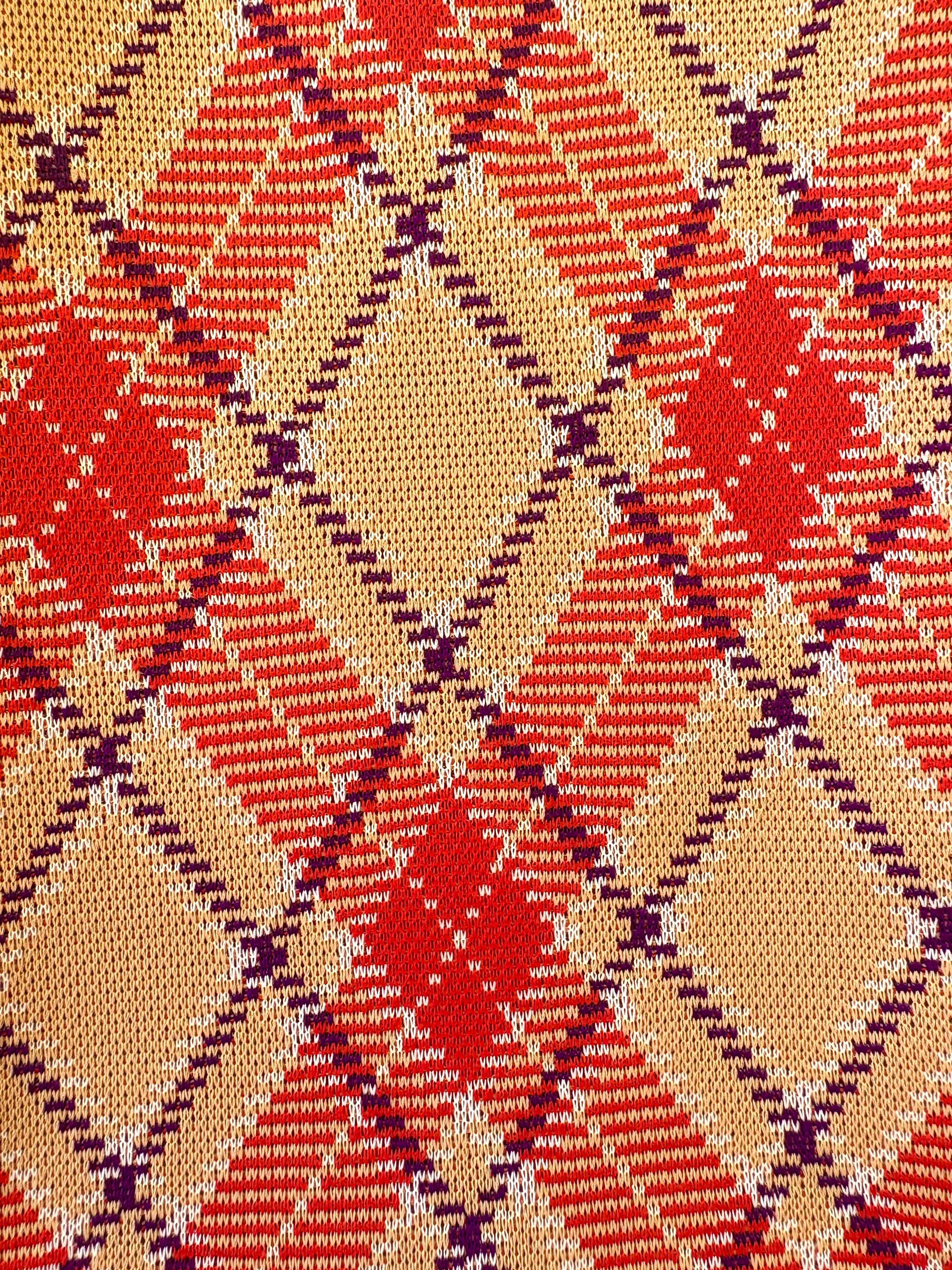 Close-up of a patterned fabric with red, beige, and purple colors.