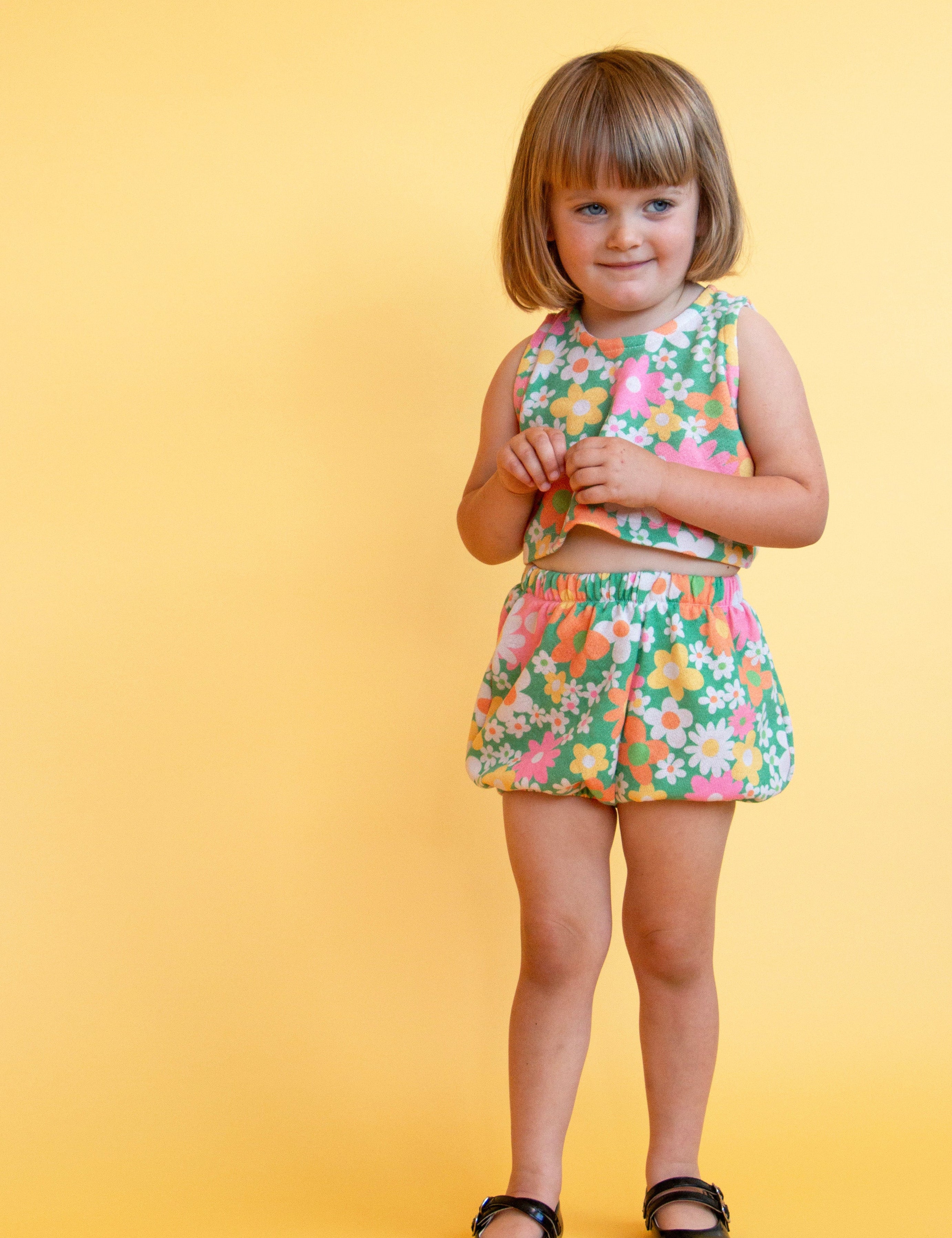 toddler girl wearing vintage inspired colorful flower power matching set with yellow background 