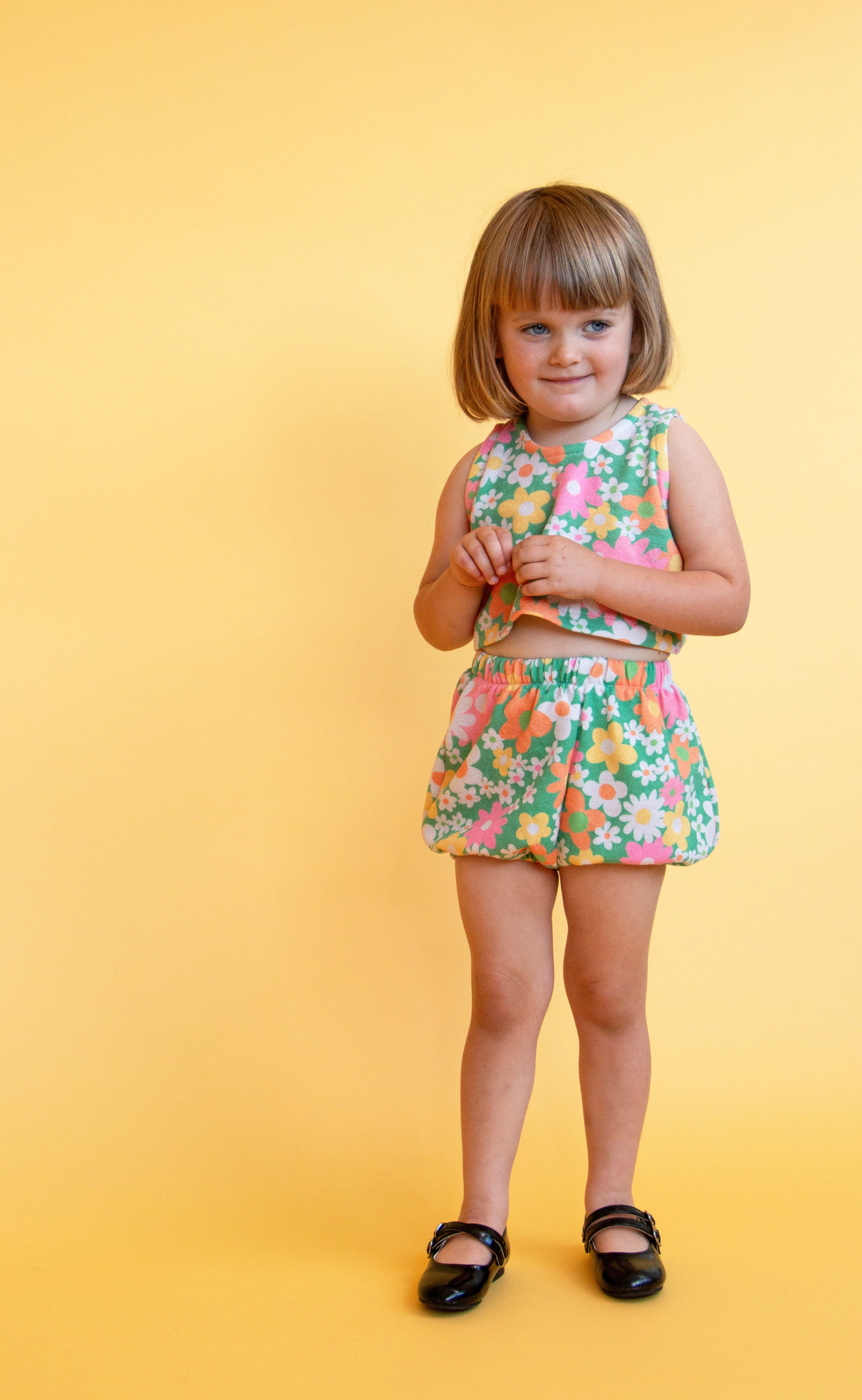 toddler girl wearing vintage inspired colorful flower power matching set with yellow background 