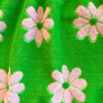 Close-up of green flower power Terry cloth fabric with pink floral patterns