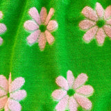 Close-up of green flower power Terry cloth fabric with pink floral patterns