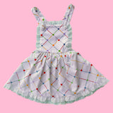 Children's dress with colorful geometric pattern on a pink background