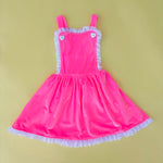 Adorable vintage inspired girls pink velvet pinafore dress for birthday party on yellow background