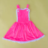Adorable vintage inspired girls pink velvet pinafore dress for birthday party on yellow background