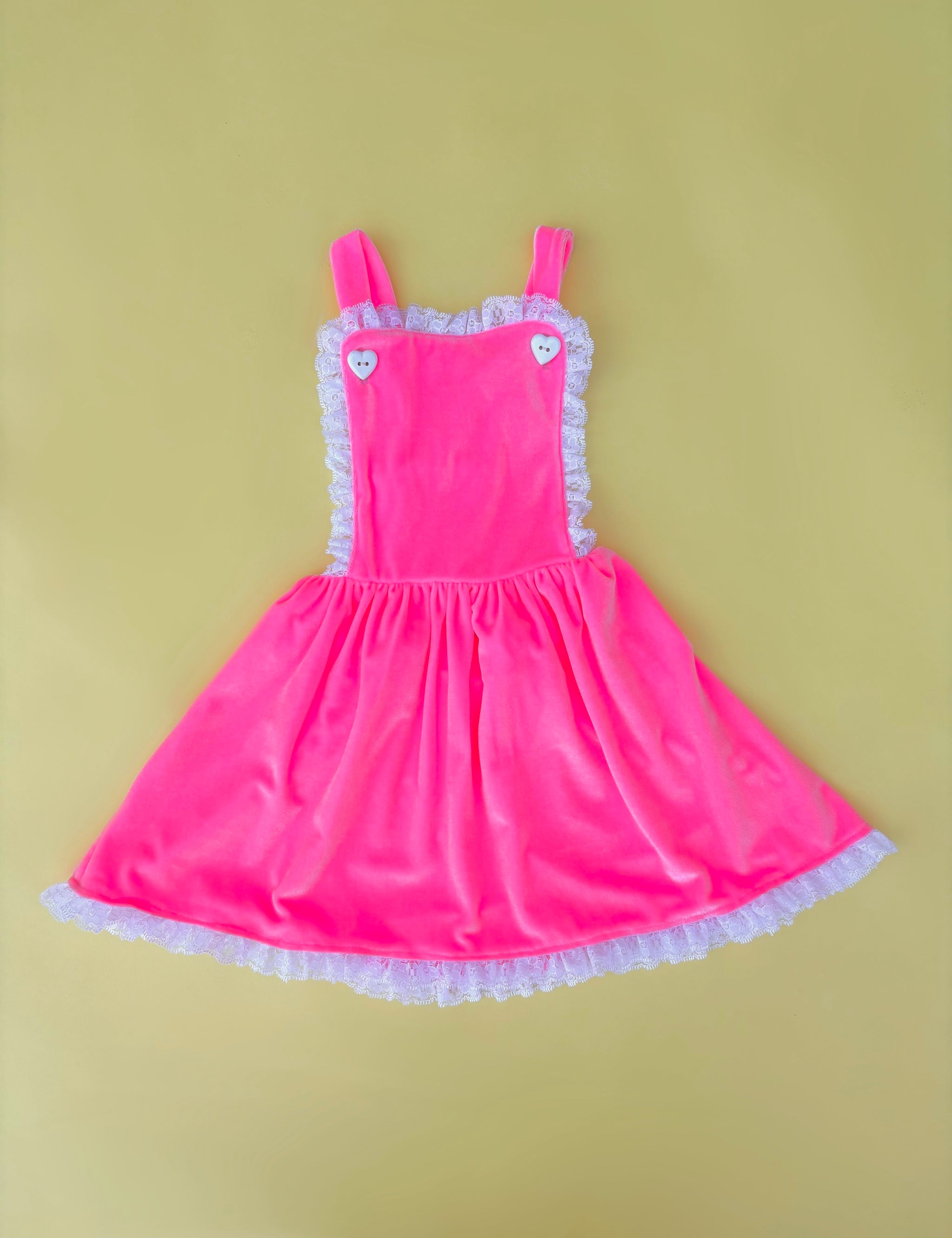 Adorable vintage inspired girls pink velvet pinafore dress for birthday party on yellow background