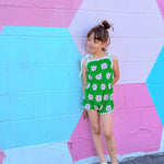girl wearing retro vibrant green colorful romper standing in front of colorful mural