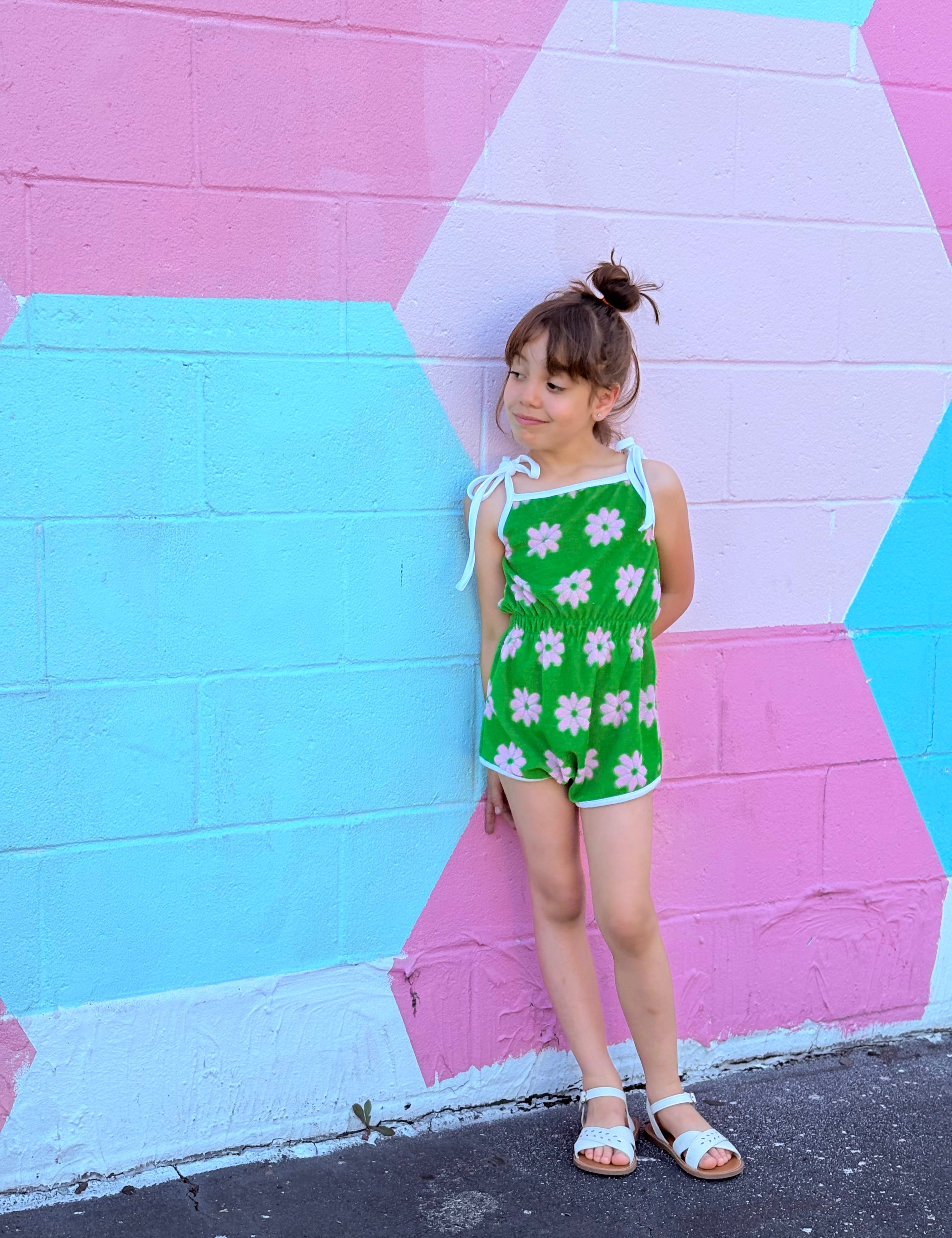 girl wearing retro vibrant green colorful romper standing in front of colorful mural