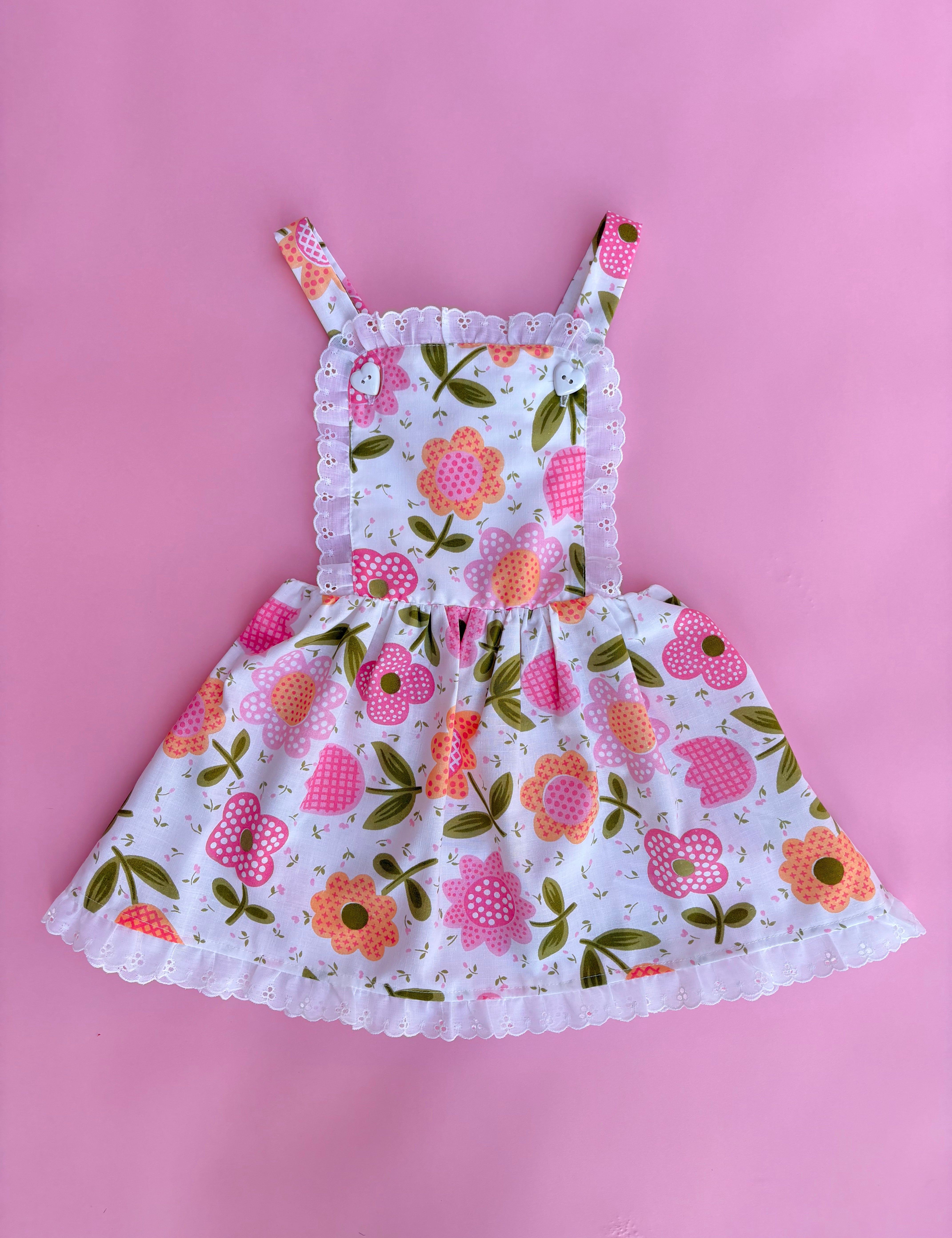 vintage inspired pink floral flower power girls pinafore dress with pink backdrop 