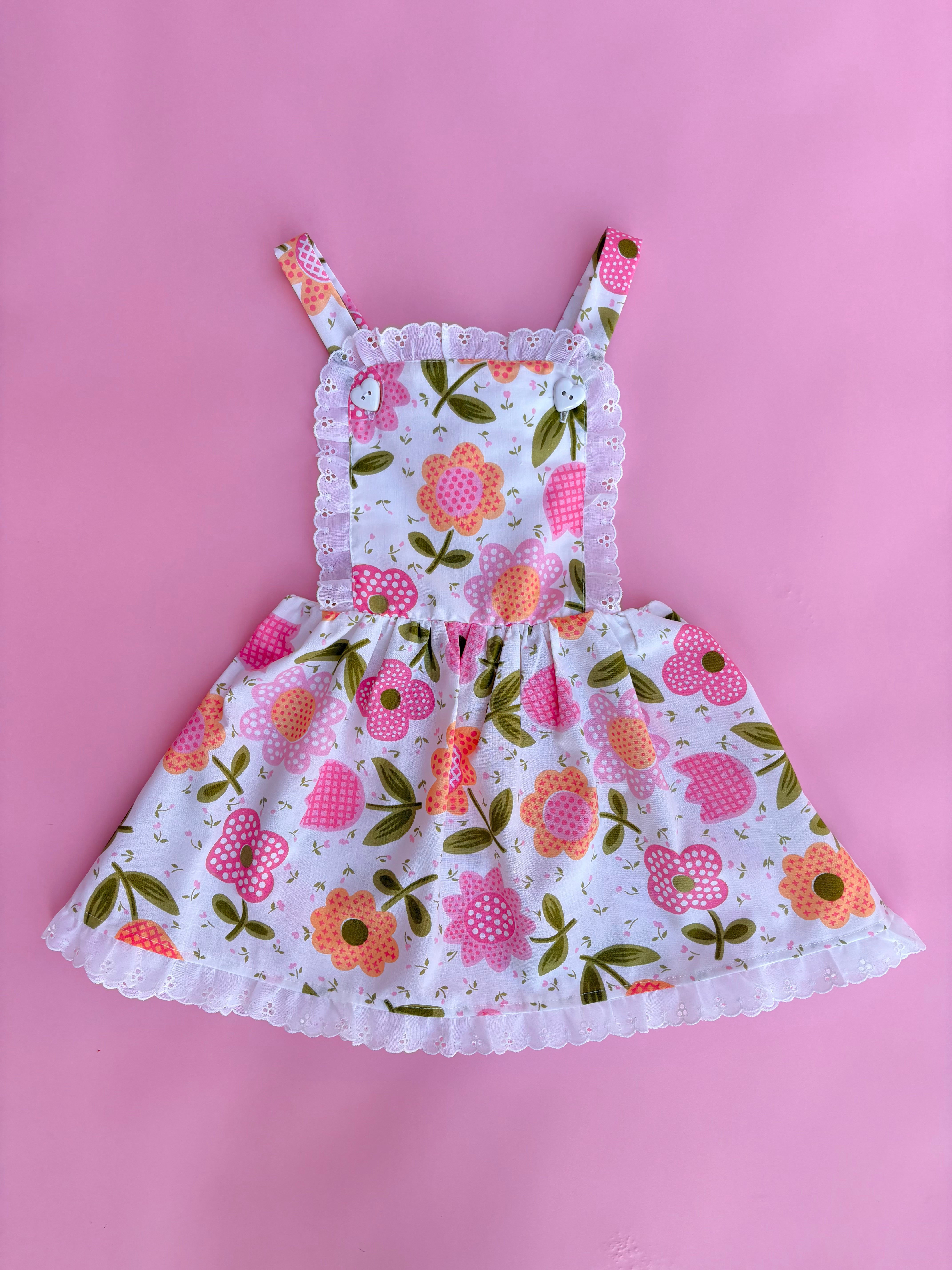 vintage inspired pink floral flower power girls pinafore dress with pink backdrop 