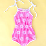 Pink floral romper with white straps on a yellow background