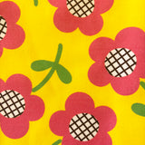 close up of 60s style fabric pattern with groovy pink flowers on yellow background