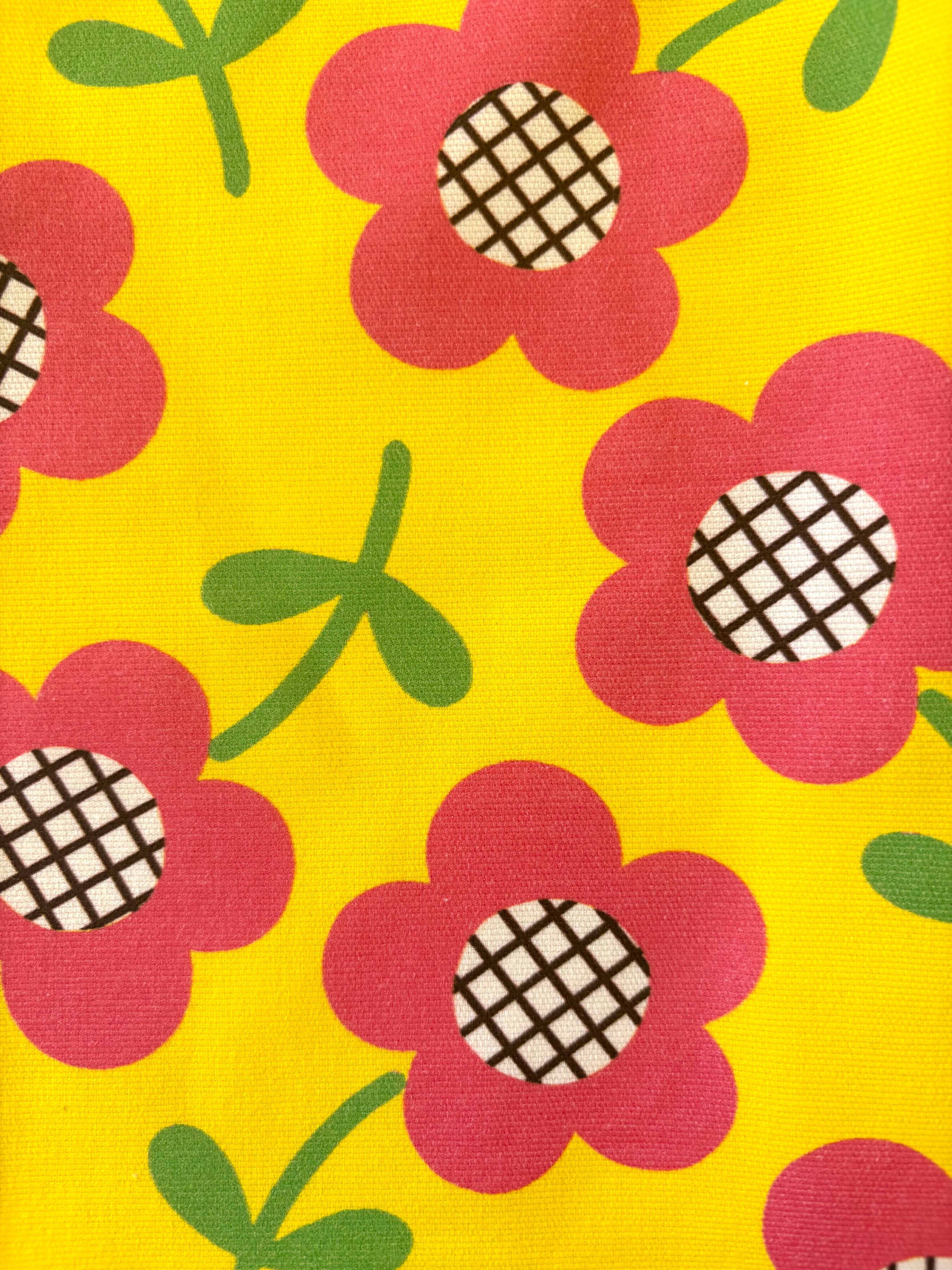 close up of 60s style fabric pattern with groovy pink flowers on yellow background