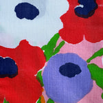 Close-up of colorful floral pattern with red, blue, and green flowers on a pink background.