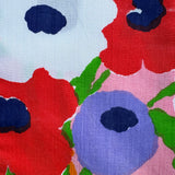 Close-up of colorful floral pattern with red, blue, and green flowers on a pink background.