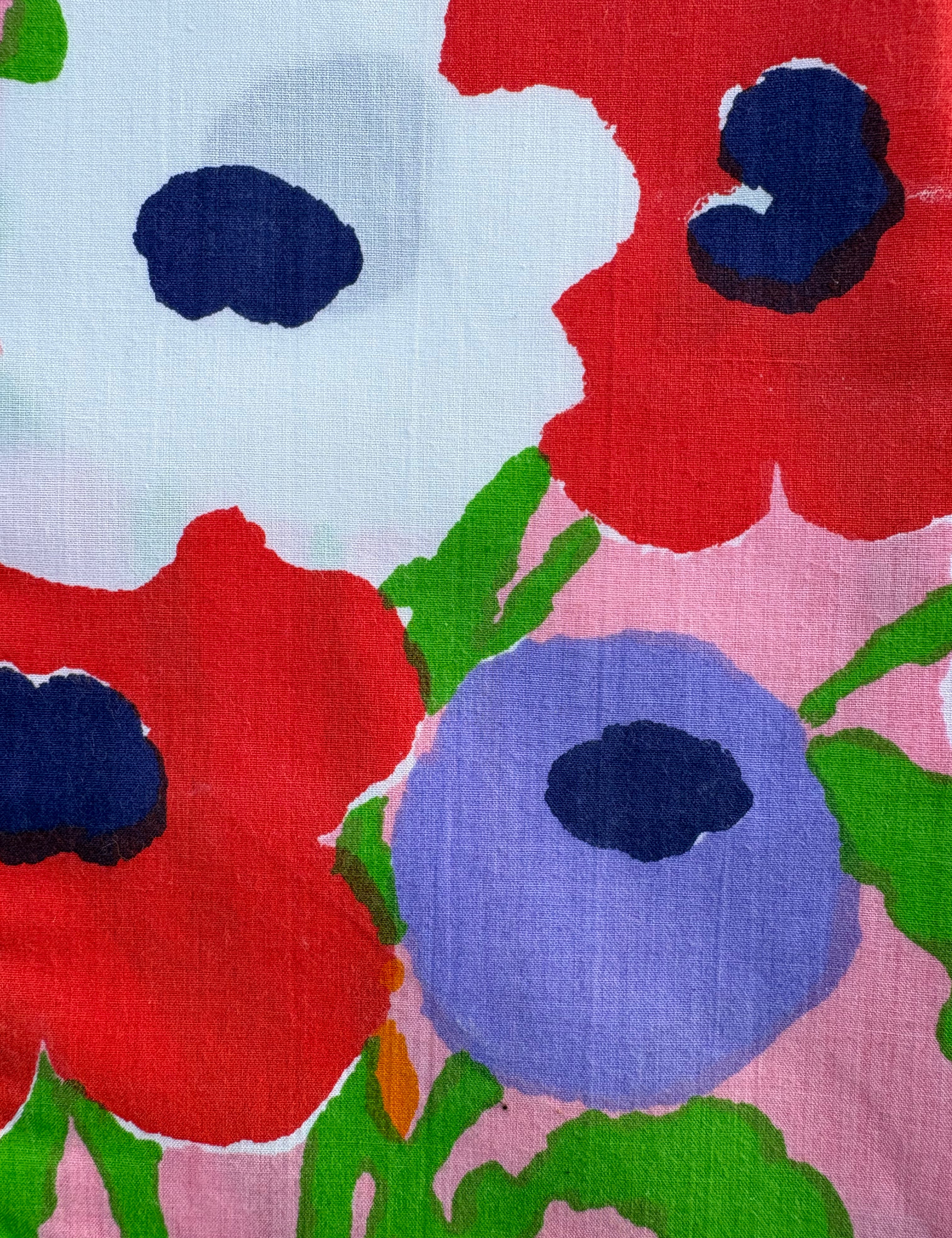 Close-up of colorful floral pattern with red, blue, and green flowers on a pink background.